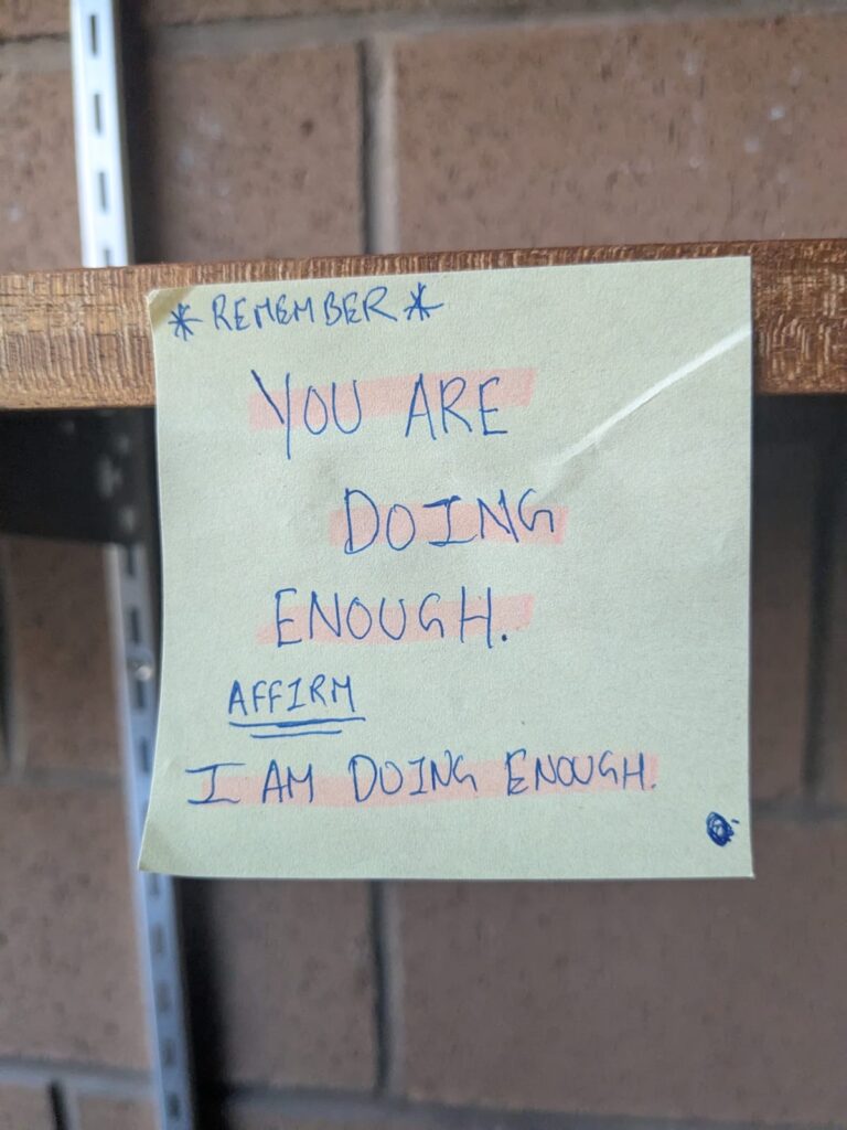 Sticky note stuck to a shelf with the words "You are doing enough." 
