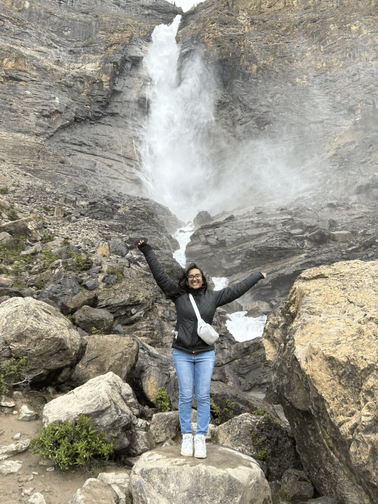 Girl standing in front of a waterfall, feeling free. 
